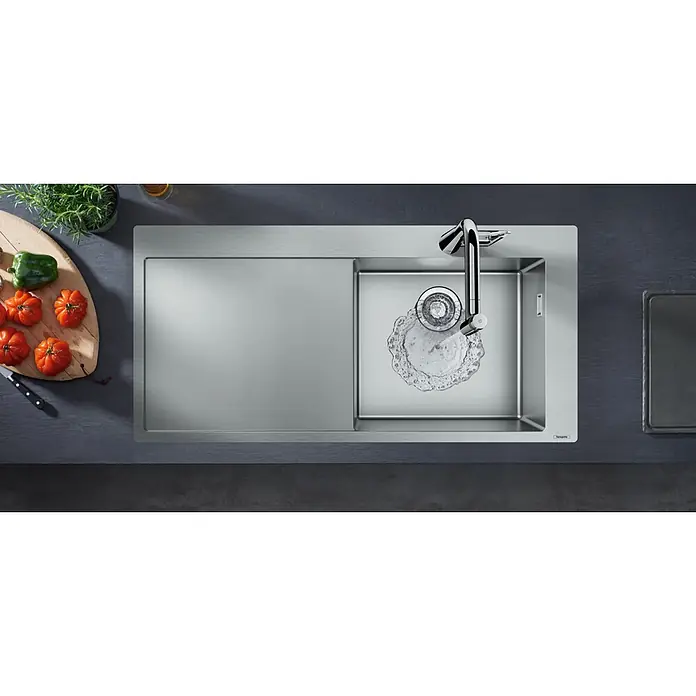 Hansgrohe Einbauspüle S715 - 104,5 x 51 cm, Edelstahl - Küchenspüle aus Edelstahl mit Abtropffläche und Chromarmatur, Wasser läuft, neben einem Schneidebrett mit frischem Gemüse.