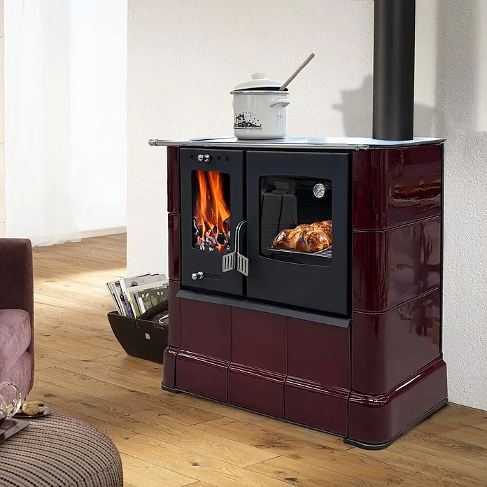 Domofire Kaminofen Sparherd Steyr M - 7,5 kW, Raumheizvermögen: 150 m³, Material Verkleidung: Keramik, Schwarz - Glänzender bordeauxroter Holzofen mit Brennkammer, Backofen und einem Topf obenauf. Brötchen backen darin, was eine warme, gemütliche Raumatmosphäre schafft.