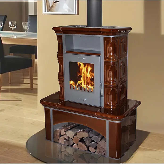 Domofire Kachelofen Bremen I. - Heizleistung: 6 kW, Kaffeebraun, Raumheizvermögen: 150 m³ - Brauner Kaminofen mit Keramikfliesen, brennendem Feuer hinter Glas und Holzscheiten im Untersockel, in einem Raum.