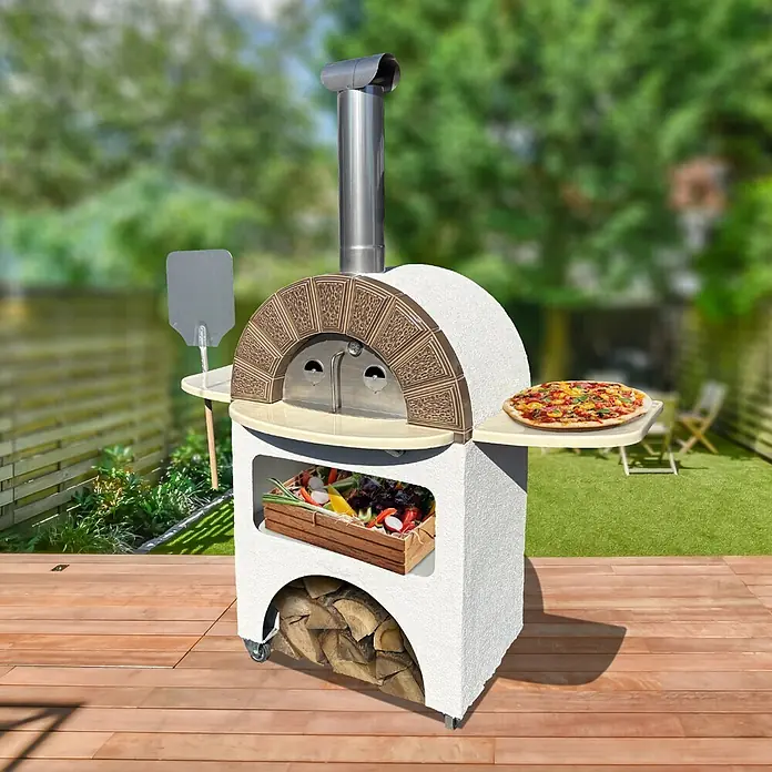 Domofire Kaminofen Capri - Material Verkleidung: Keramik, Weiß - Weißer Outdoor-Pizzaofen mit braunem Ziegelbogen, Edelstahlkamin und Ablagen, auf Holzterrasse, mit Pizza und Zutaten.