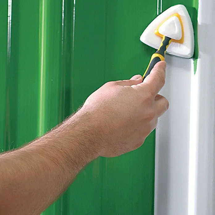 Lehnartz Isi-Line Streicher-Set Premium Delta 3-in-1 - 5 -tlg. - Nahaufnahme eines Mannes, der mit einem dreieckigen Pinsel grüne Farbe auf eine weiße Ecke aufträgt.