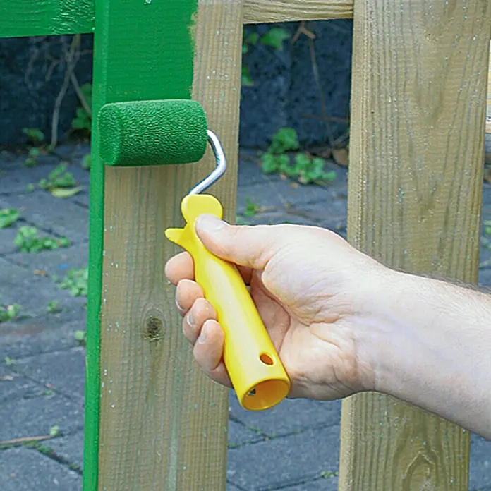 Lehnartz Isi-Line Streicher-Set Roll-On - 3 -tlg. - Das Bild zeigt eine Hand, die mit einer Farbwalze einen Holzzaun grün streicht. Die Farbwalze hat einen gelben Griff.