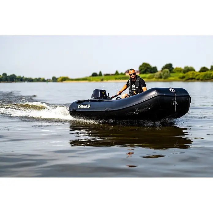 Tohatsu Schlauchboot-Set MFS 5 DDS Motor & Allroundmarin T320 Schlauchboot - Motorleistung: 3,7 kW - Mann fährt ein schwarzes Schlauchboot mit Außenbordmotor auf dem Wasser, das eine Heckwelle erzeugt.