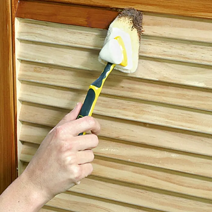 Lehnartz Isi-Line Streicher-Set Premium Delta 3-in-1 - 5 -tlg. - Eine Hand hält einen gelben und schwarzen Griff mit einem angebauten Staubwedel zum Reinigen von Jalousien.