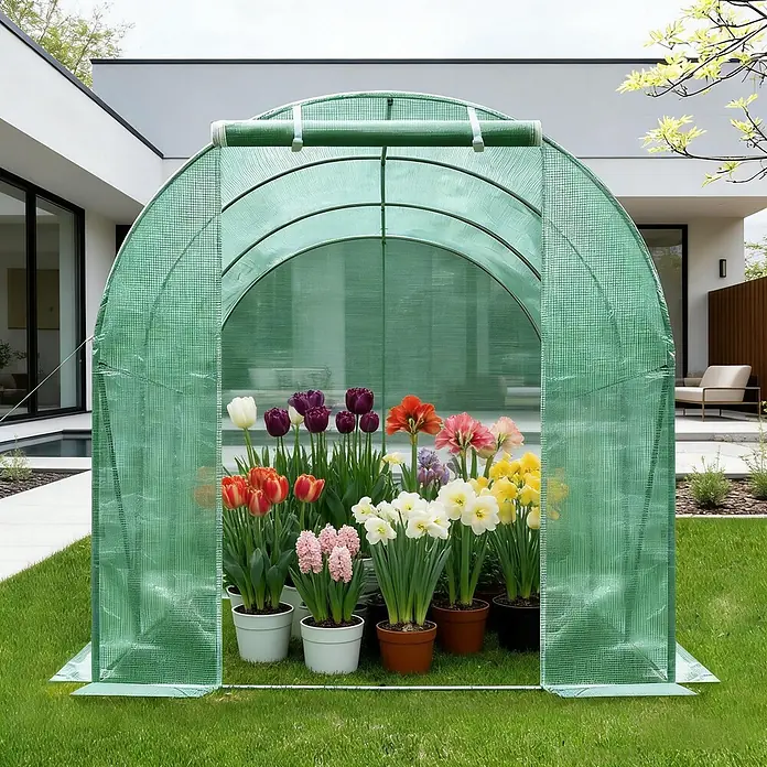 SONNENH Gewächshaus - 200 x 300 cm, Material Seitenwand: Kunststoff, Grün - Grünes bogenförmiges Mini-Gewächshaus mit offener Front und aufrollbarer Tür, gefüllt mit bunten Topfblumen auf einem Rasen.