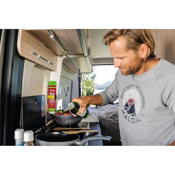 Abus Feuerlöschspray AFS625 - Geeignet für: Elektrische Anlagen bis 1.000 V (min. Abstand 1 m), 625 ml - Rotes ABUS Feuerlöschspray mit grüner Kappe an der Wand einer Camper-Küche befestigt.