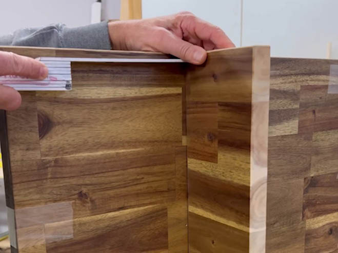Eine Holzplatte wird an einer anderen festgemacht im rechten Winkel