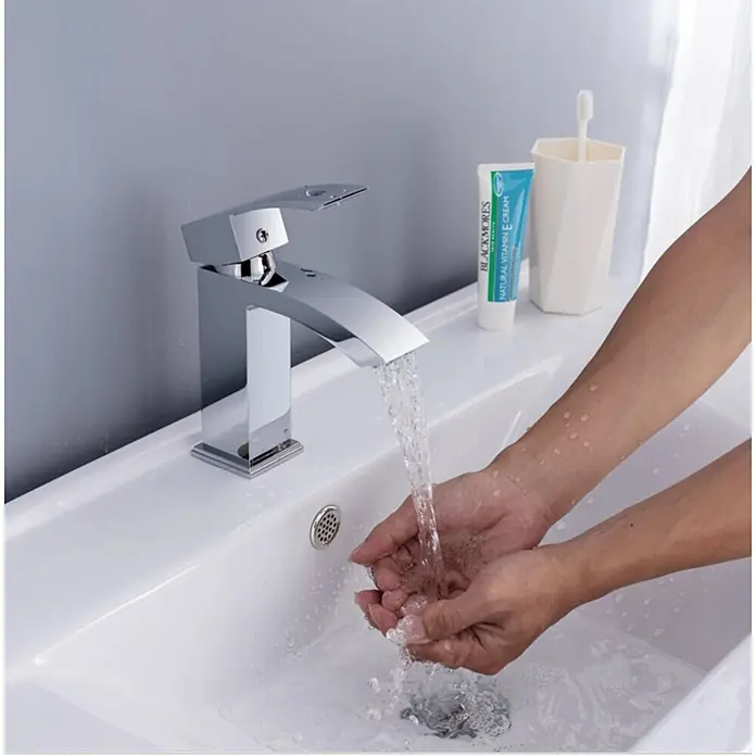 Hudor Waschtischarmatur 02111cw -  - Moderner Chrom-Wasserhahn, der Wasser in Hände in einem weißen Waschbecken gießt, seine Eleganz und Funktion zeigend.