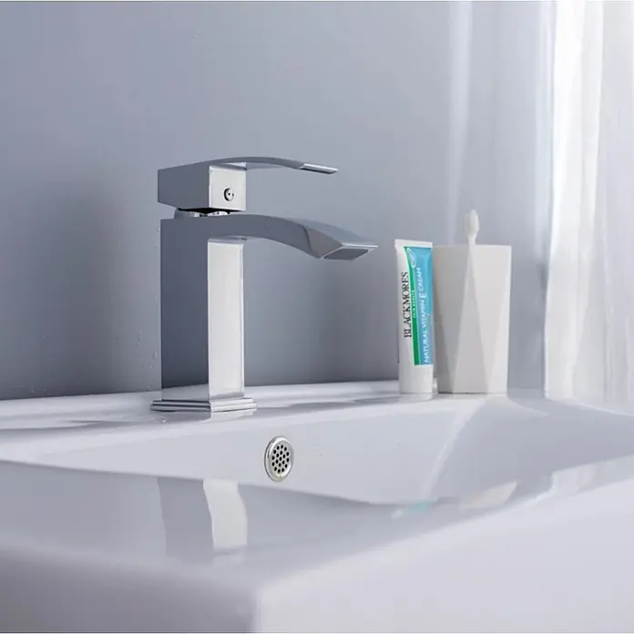Hudor Waschtischarmatur 02111cw -  - Moderner Chrom-Badezimmerwasserhahn mit schlankem Design, in einem weißen Waschbecken mit Toilettenartikeln daneben.