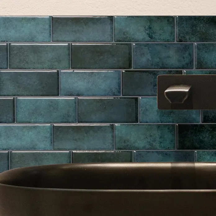 Smart Tiles Selbstklebemosaik Metro - 29,34 x 21,28 cm, Medina, Glänzend - Mattschwarzer Wandhahn über dunklem Becken, vor glänzenden teal-farbenen U-Bahn-Fliesen.