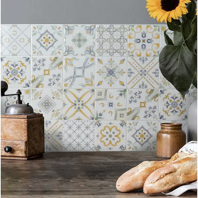 Smart Tiles Selbstklebemosaik Vintage - 22,86 x 22,86 cm, Veletti, Glänzend - Dekorative gemusterte Wandfliesen in Weiß mit blauen, gelben und grünen Mustern im mediterranen Stil als Küchenrückwand.