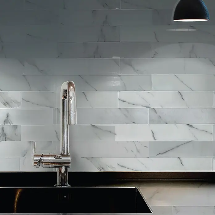 Smart Tiles Selbstklebemosaik Norway - 57,31 x 49,4 cm, Asti, Matt - Weiße, rechteckige Fliesen mit Marmor- und Milchglas-Optik als Küchenrückwand, mit Armatur und dunkler Arbeitsplatte.