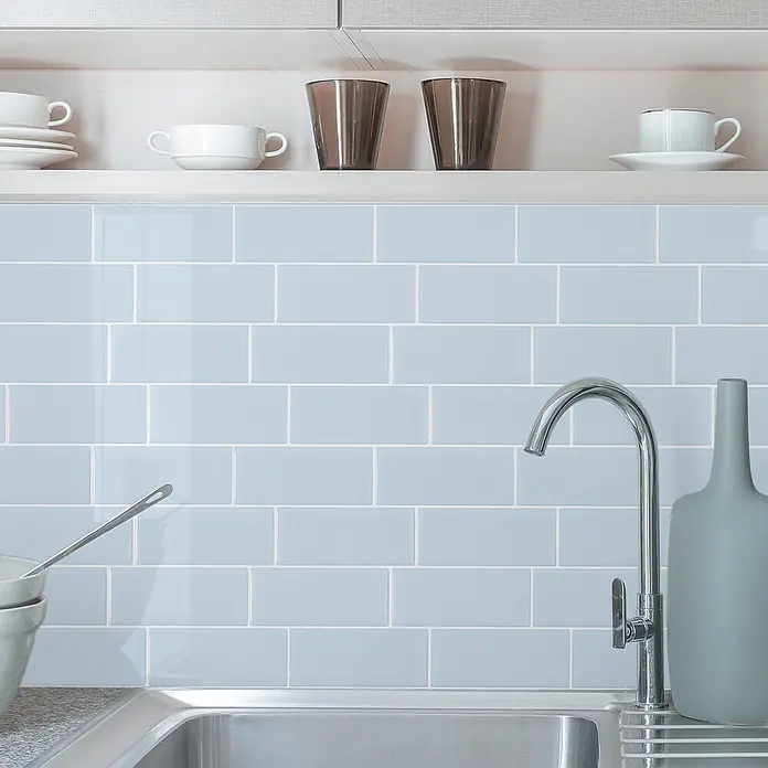Smart Tiles Selbstklebemosaik Metro - 29,34 x 21,28 cm, Babe, Glänzend - Hellblaue, glänzende Metro-Fliesen als Küchenrückwand über einer Spüle.