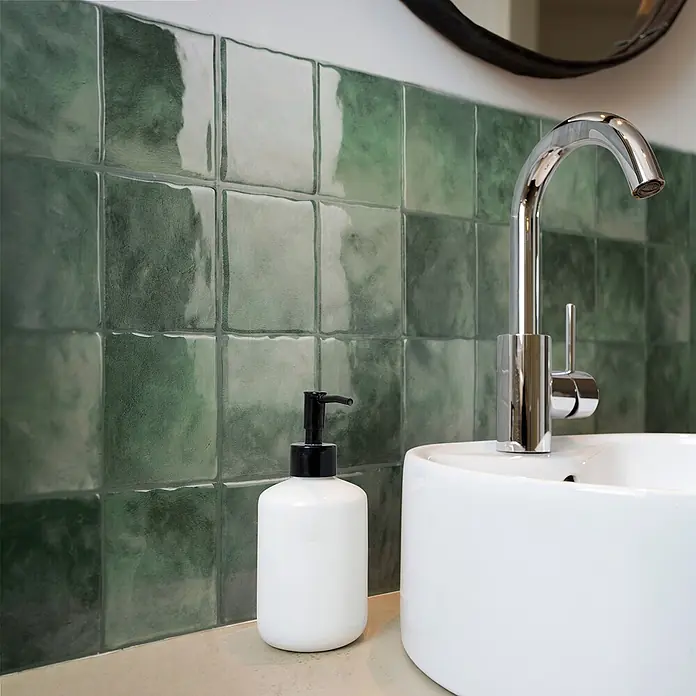 Smart Tiles Selbstklebemosaik Zellige - 22,86 x 22,86 cm, Taza, Glänzend - Weißes Keramik-Aufsatzwaschbecken mit Chromarmatur und weißem Seifenspender auf einer Arbeitsplatte.