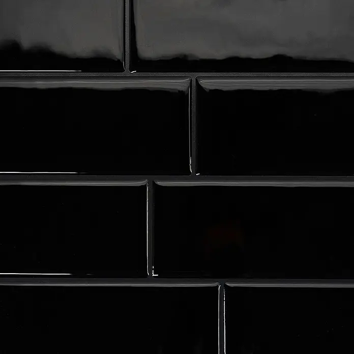 Smart Tiles Selbstklebemosaik Metro - 29,34 x 21,28 cm, Nero, Glänzend - Nahaufnahme von glänzenden schwarzen U-Bahn-Fliesen mit abgeschrägten Kanten, in einem Ziegelmuster angeordnet.