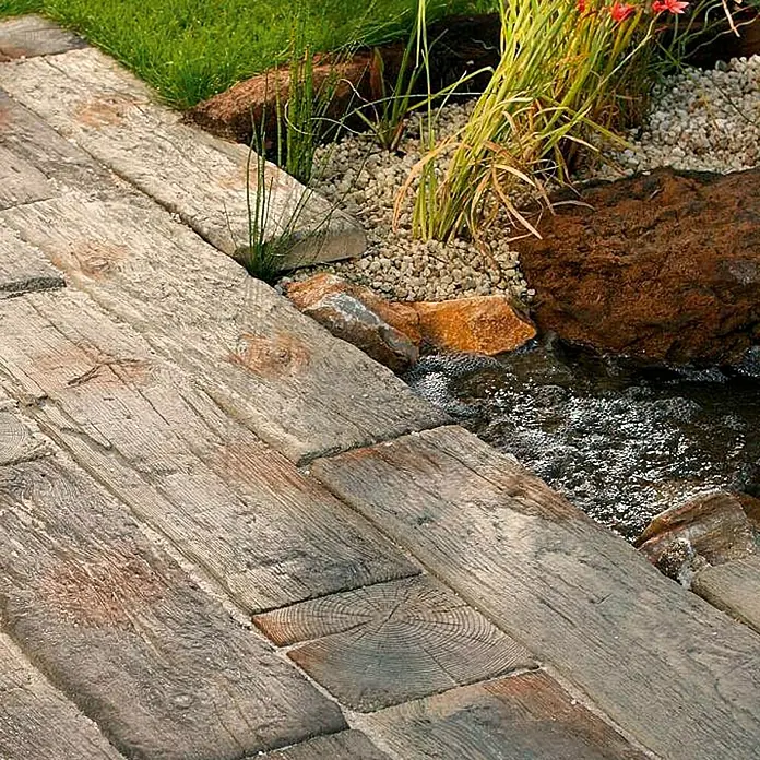 EHL Gehwegplatte Bahnschwelle22,5 x 22,5 x 4 cm, Naturbraun-grau, Beton - Holzweg neben dem Wasserlauf.