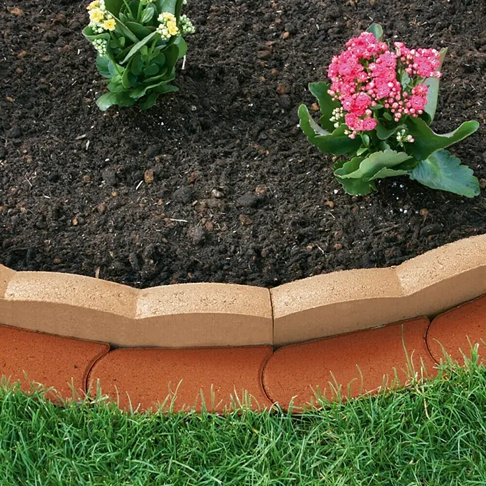 Christoph Mähstein - 22 x 10 x 4,5 cm, Toskana, Beton - Nahaufnahme einer stilvollen Gartenumrandung aus Ziegelsteinen, die ein Blumenbeet mit blühenden Pflanzen von einem saftig grünen Rasen trennt.