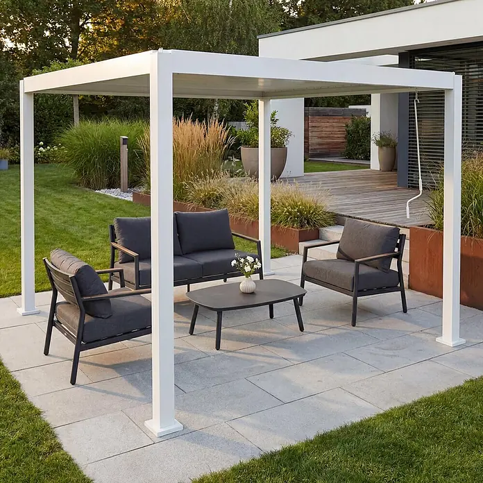 Berlinlodge Pergola mit Lamellendach - B x T: 300 x 300 cm, Farbe Gestell: Weiß, Metall - Eine weiße moderne Pergola überdacht eine dunkelgraue Outdoor-Lounge-Gruppe mit Sofa, zwei Sesseln und einem Couchtisch auf einer Terrasse.