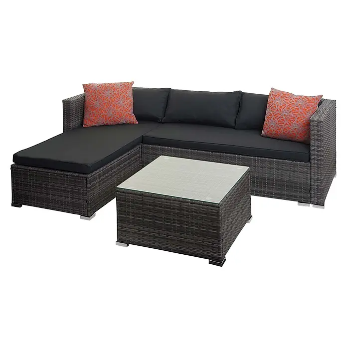 Mendler Loungemöbel-Set HWC-F57 - 3 -tlg., Polyrattan, Grau, Kissen dunkelgrau mit Deko-Kissen, Grau, dunkelgrau - Dunkelgraue Rattan-Ecksofa mit schwarzen Kissen, orangefarbenen gemusterten Kissen und passendem Couchtisch mit Glasplatte.