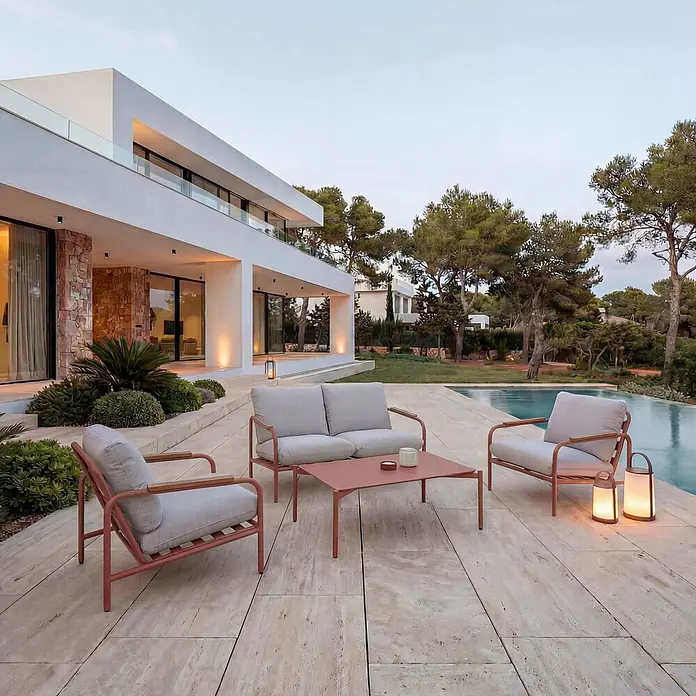 Mendler Alu-Gartengarnitur HWC-O11 2-Sitzer - terrakotta Polster beige -  - Outdoor-Lounge-Set mit terrakottafarbenem Rahmen und hellen Kissen, dazu ein Couchtisch, auf einer Terrasse am Pool.