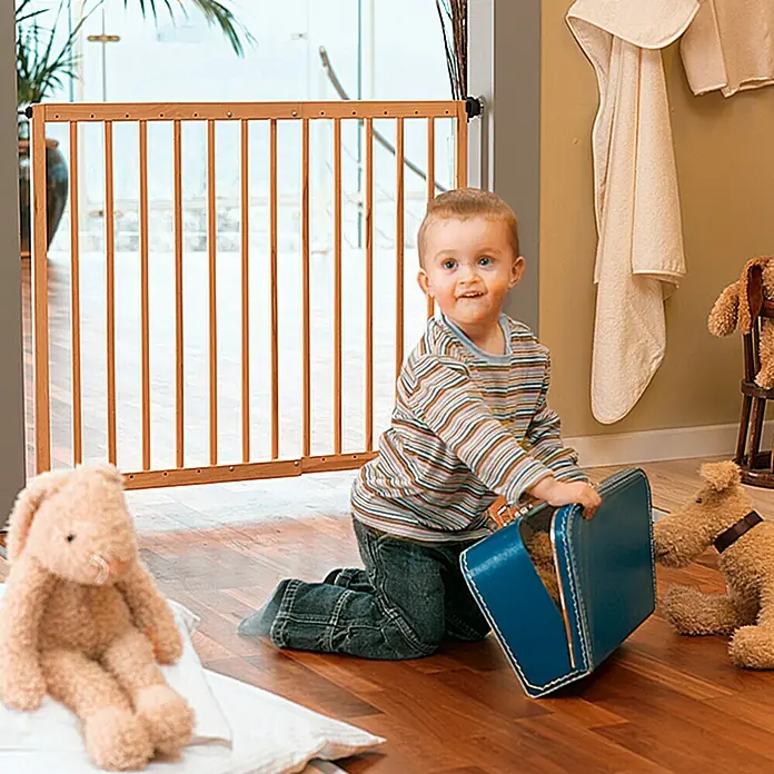 Star Stairs Sicherheitsgitter Svea - Höhe: 70 cm, Verstellbar: 61 cm - 101,7 cm - Holztürgitter sichert den Durchgang, während ein Kind mit Spielzeug spielt, um Sicherheit und Unterhaltung zu gewährleisten.