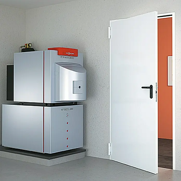 Hörmann Brandschutztür H8-5 - 87,5 x 187,5 cm, Links/Rechts, Grauweiß - Ein modernes Viessmann Heizsystem in einem Kellerraum, neben einer offenen weißen Tür. Die Heizungsanlage steht auf einem grauen Betonsockel.
