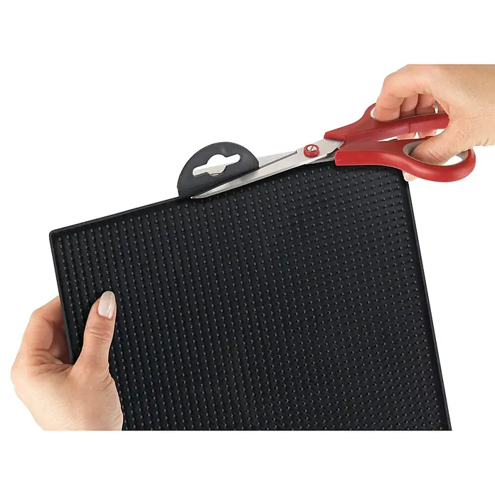 Wenko Abtropfmatte Maxi - 400 x 300 mm, Schwarz - Schwarze strukturierte Matte wird mit roter Schere geschnitten.