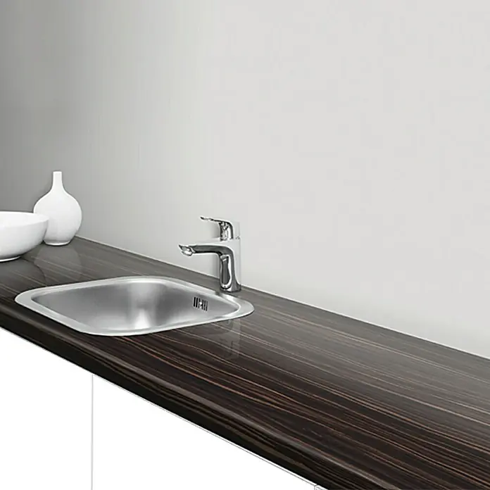 Resopal Premium Encimera de cocina al corte - Macassar, Espesor: 3,8 cm, Ancho: 60 cm - Una vista cercana de un fregadero moderno con grifo sobre una encimera oscura, junto a un cuenco y un jarrón.