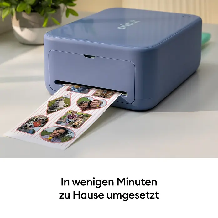 Cricut Drucker Stickerpix Print & Cut Essential-Bundle - Pastellblau, 28,7 x 20,3 x 10,4 cm - Ein hellblauer Cricut-Drucker steht auf einer hellen Oberfläche und druckt eine Reihe personalisierter Fotoaufkleber.