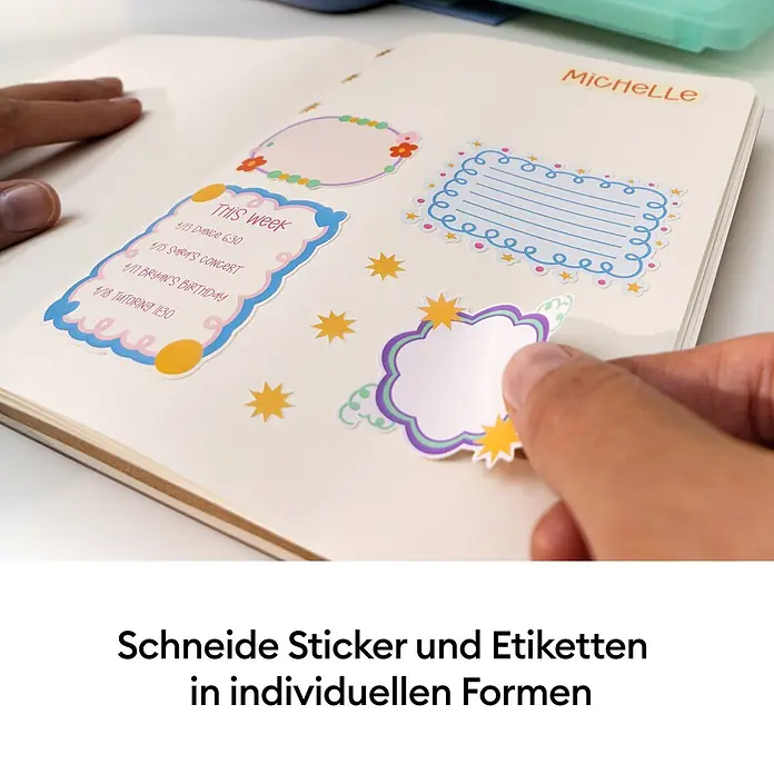 Cricut Drucker Stickerpix Print & Cut Essential-Bundle - Pastellblau, 28,7 x 20,3 x 10,4 cm - Hand platziert einen bunten Wolken-Sticker in einem Notizbuch mit weiteren dekorativen und Agenda-Stickern.