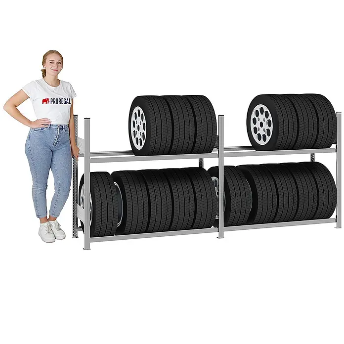 Proregal Reifenregal TIRE PRO 150cm Feldbreite - H x B x T: 115 x 260 x 43 cm, Stecken, Verzinkt - Graues Metallreifenregal mit zahlreichen Autoreifen, eine Frau steht daneben als Größenvergleich.