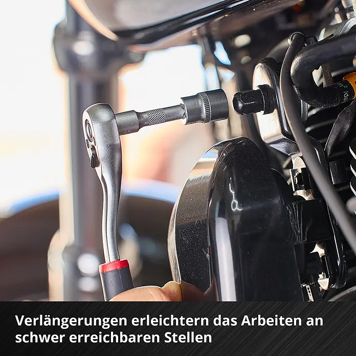 Einhell Werkzeugsatz-Einlage E-Case Stecknuss- und Ratschenset - 60 -tlg. - Ein silberner Ratschenschlüssel mit Verlängerung und Stecknuss wird an einem Motorradmotor verwendet, um eine schwer zugängliche Schraube zu erreichen.