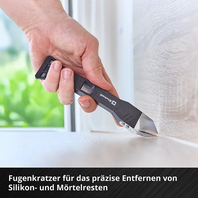 Einhell Werkzeugkoffer E-Case Renovierung - 78 -tlg. - Hand verwendet einen schwarzen und silbernen Einhell Fugenkratzer zum präzisen Entfernen von Dichtstoffresten.