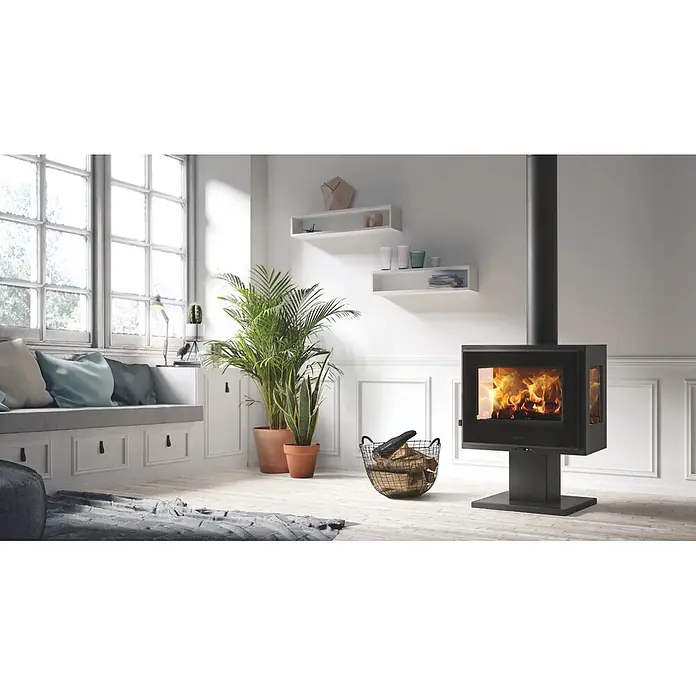 Panadero Estufa de leña Atlantic 3V - 5,9 kW, Volumen de calefacción: 180 m³, Negro - Estufa de leña negra moderna con fuego visible, calentando un salón luminoso. Se alza sobre un pedestal, con cristal en dos lados.