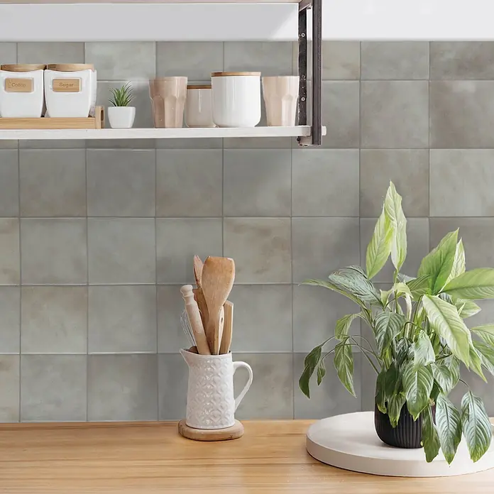 Smart Tiles Selbstklebemosaik Zellige - 22,86 x 22,86 cm, Fez, Matt - Küchenzeile mit weißen Kaffee- und Zuckerdosen, Holzbesteck und Pflanze.