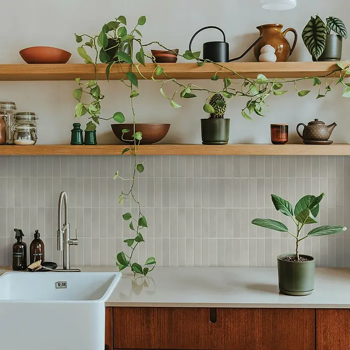 Smart Tiles Selbstklebemosaik Morocco - 29,02 x 22,86 cm, Essaouira, Glänzend - Hellgraue vertikal verlegte Rechteckfliesen bilden einen Küchenrückwand über einem Spülbecken unter Holzregalen.