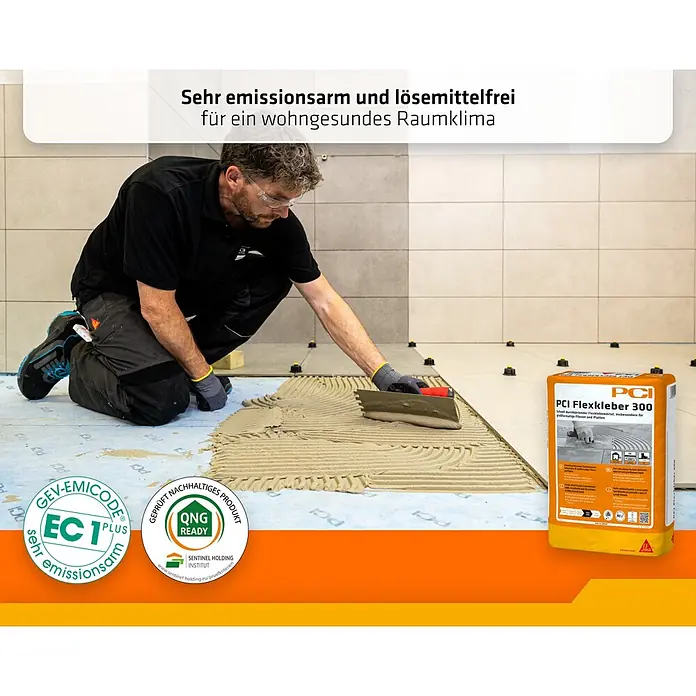 PCI Flexkleber 300 20 kg C2E S1 Großformat - 20 kg - Eine Person verteilt PCI Flexkleber 300 Fliesenkleber auf dem Boden. Rechts ist der orange-gelbe Produktsack zu sehen.