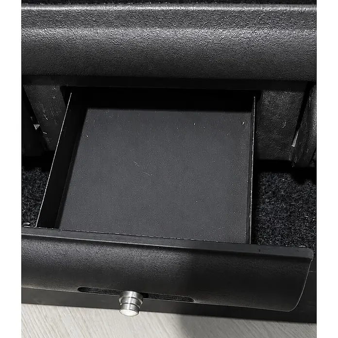 Insert de leña Koni - L x An x Al: 44,5 x 80 x 58,3 cm, 11,6 kW, 295 m³, Negro - Cajón/bandeja de almacenamiento de coche negro abierto con tirador plateado, mostrando su interior. Hecho de plástico oscuro texturizado.