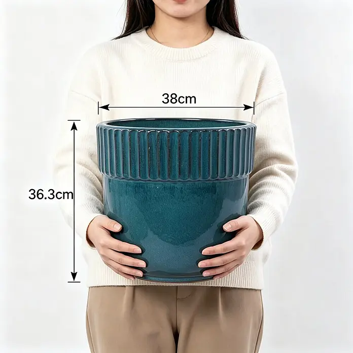 SONNENH Pflanztopf - 1 Stk., Keramik, Blau - Großer türkisfarbener Keramik-Pflanztopf mit gerilltem Rand, von einer Person gehalten. Maße: 38 cm breit, 36,3 cm hoch.