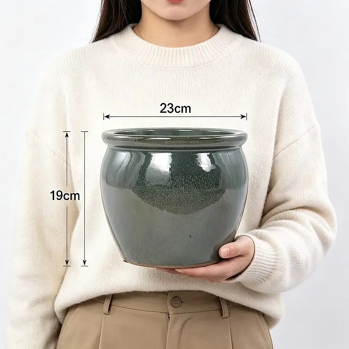 SONNENH Pflanztopf - 1 Stk., Keramik, Grün - Dunkelgrüner glasierter Keramiktopf, von Person gehalten, mit 23 cm Durchmesser und 19 cm Höhe.