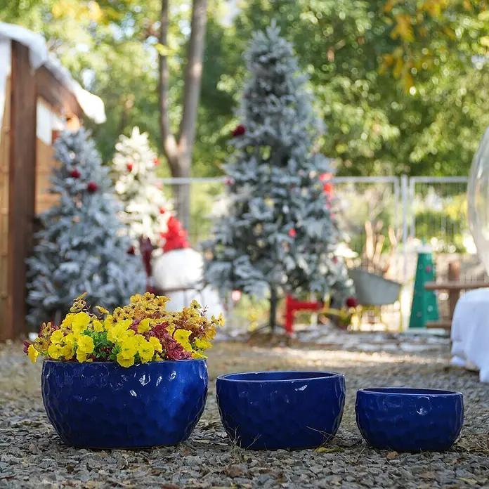 SONNENH Pflanztopf - 3 Stk., Keramik, Blau - Drei blaue, strukturierte Keramik-Pflanzgefäße im Freien. Das größte enthält gelbe und rote Blumen.