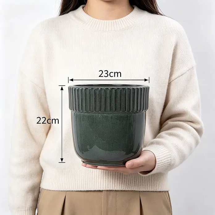 SONNENH Pflanztopf - 1 Stk., Keramik, Grün - Dunkelgrüner Keramik-Blumentopf mit geripptem Rand, 23cm breit, 22cm hoch, von einer Person gehalten.
