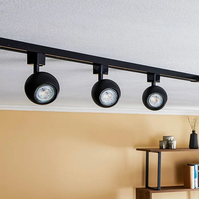 Prios LED-Spannseilsystem Felipo - schwarz, schwarz - Schwarzes Stromschienensystem mit drei kugelförmigen Strahlern über einer beigen Wand.