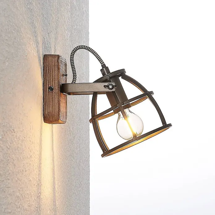 Lindby Wandleuchte innen in schwarz, braun, Wandstrahler -  - Wandleuchte mit rustikalem Holzsockel und dunklem Metallkäfigschirm, mit glühender Glühbirne.