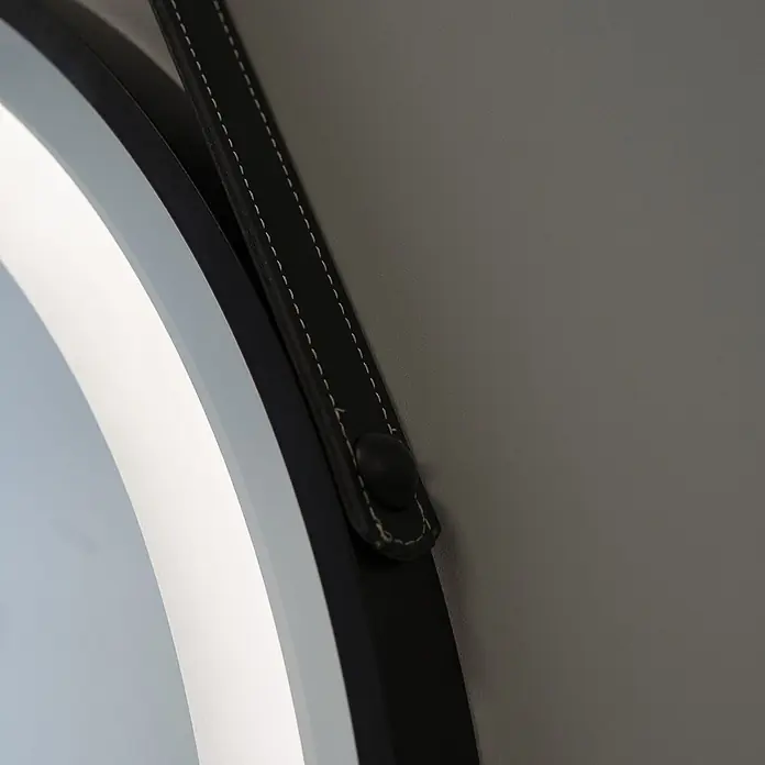 Kiamami Valentina Lichtspiegel - 0,02 x 600 cm, Schwarz - Nahaufnahme eines runden Spiegels oder einer Leuchte mit schwarzem Rahmen und beleuchtetem Innenring, ergänzt durch einen schwarzen Kunstlederriemen mit weißen Nähten.