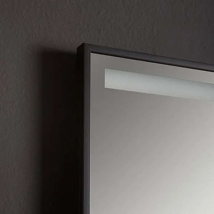 Kiamami Valentina Lichtspiegel - 20 x 700 cm, Schwarz - Dunkel gerahmter Spiegel mit integriertem LED-Lichtstreifen, an einer dunklen strukturierten Wand.