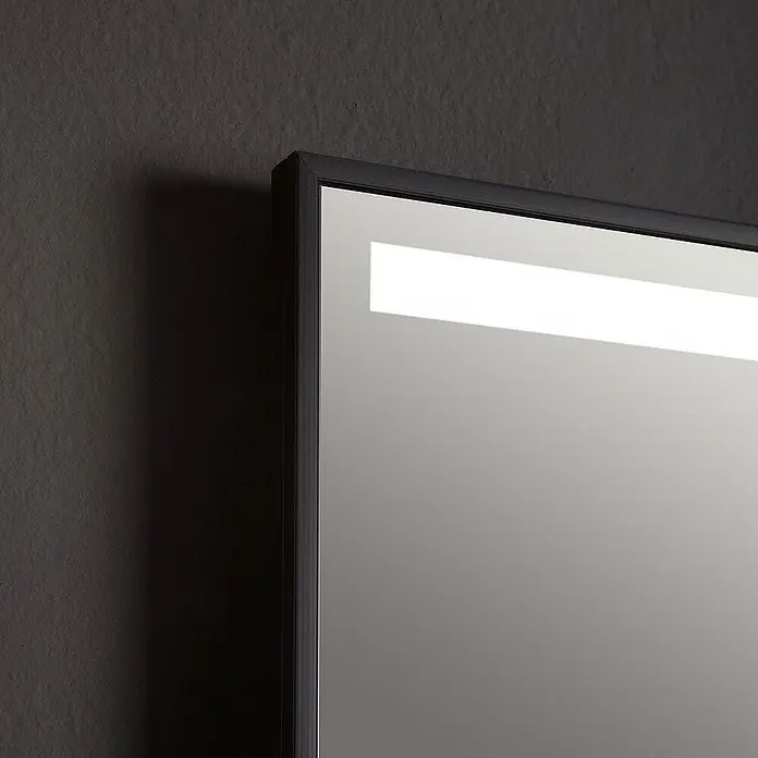 Kiamami Valentina Lichtspiegel - 20 x 700 cm, Schwarz - Rechteckiger Spiegel mit dunklem Rahmen und integriertem oberen Lichtstreifen an einer dunklen, strukturierten Wand.