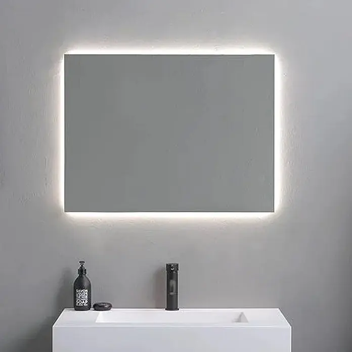 Kiamami Valentina Lichtspiegel - 22 x 600 cm, Farblos - Rechteckiger Spiegel mit warmer LED-Hintergrundbeleuchtung, montiert über einem weißen Waschbecken mit schwarzem Wasserhahn.