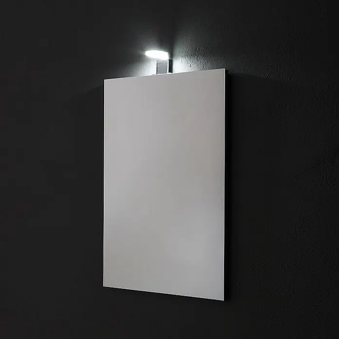 Kiamami Valentina Lichtspiegel - 20 x 700 cm, Farblos - Rechteckiger Wandspiegel mit integrierter LED-Beleuchtung oben, die den oberen Spiegelrand und die dunkle Wand beleuchtet.