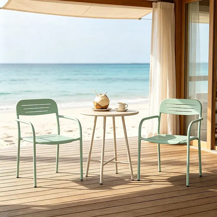 SONNENH Garten-Stapelstühle aus Metall, 2er-Set, Salbeigrün -  - Zwei hellgrüne Outdoor-Stühle und ein beiger runder Tisch auf einer Holzterrasse am Strand mit Kokosnussgetränk und Kaffee.